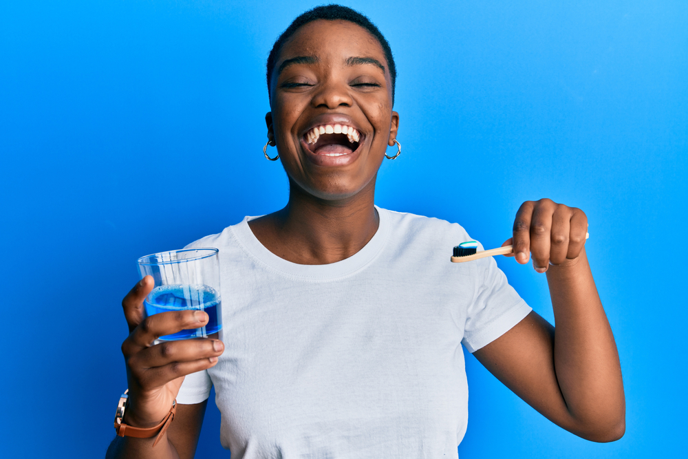 woman with mouthwash and a toothbrush